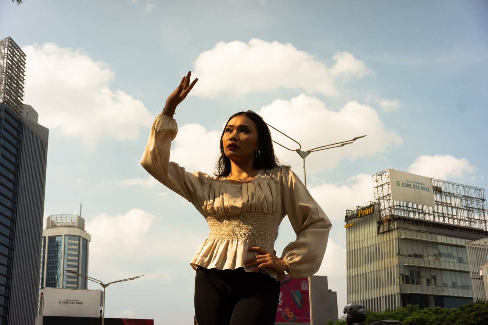 Woman raises and confidently against city backdrop, showcasing modern urban fashion.