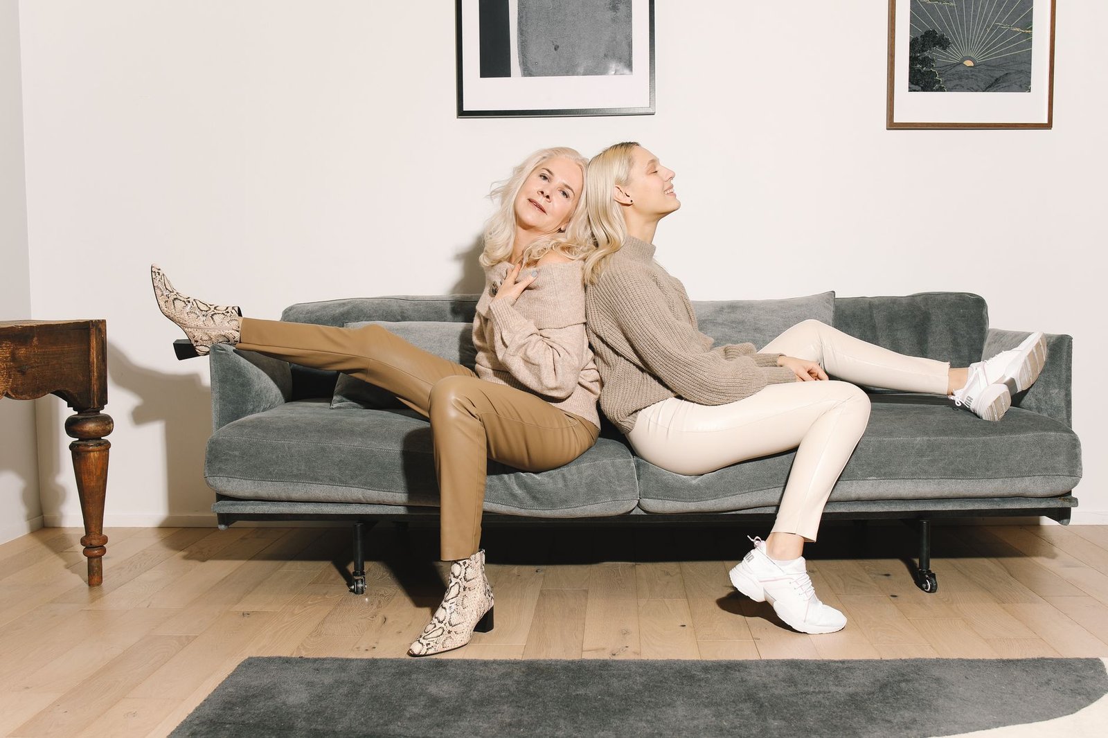 A fashionable mother and daughter duo enjoy cozy time on a sofa indoors.