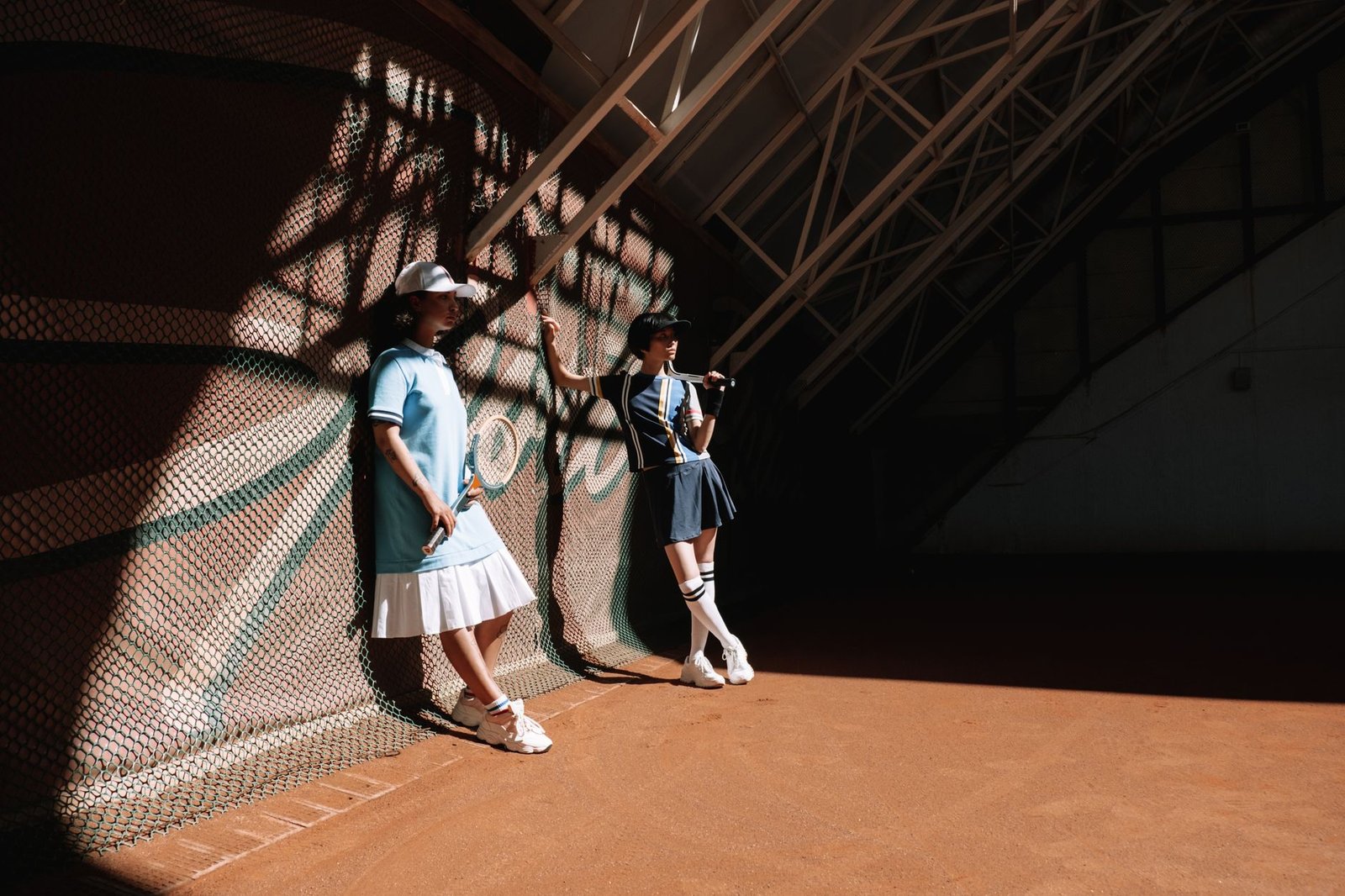 Tennis players posing indoors with sporty outfits and tennis rackets.