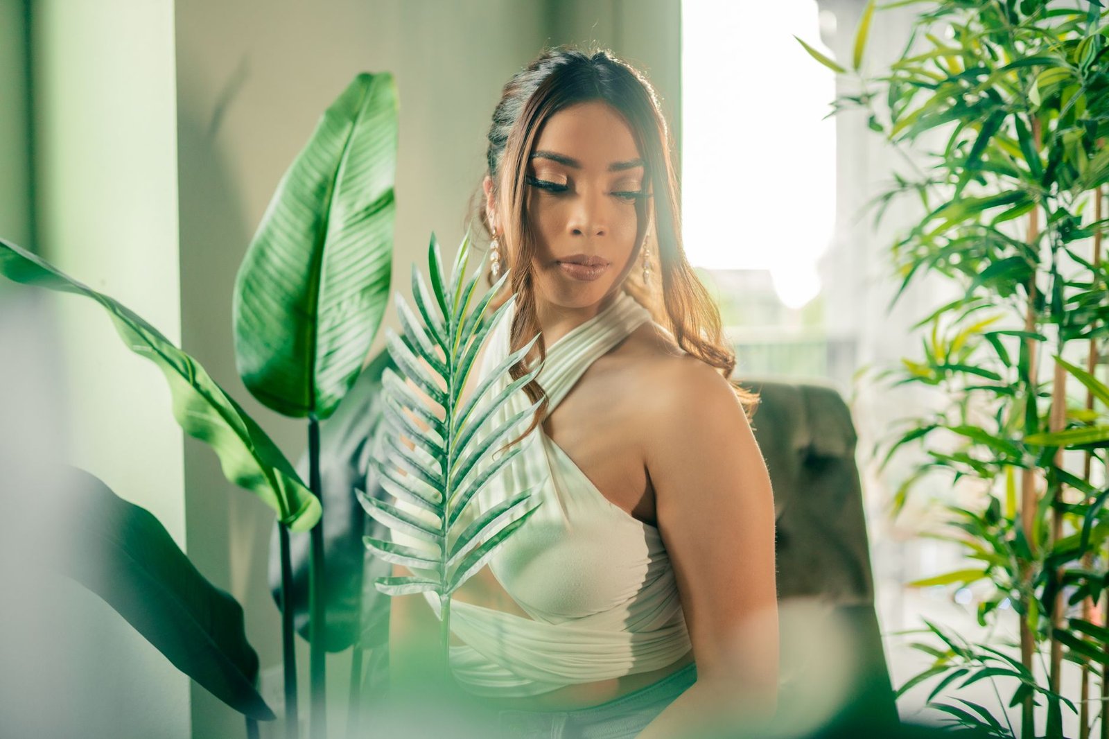 Woman in a stylish halter top surrounded by vibrant ind or plants, exuding elegance.