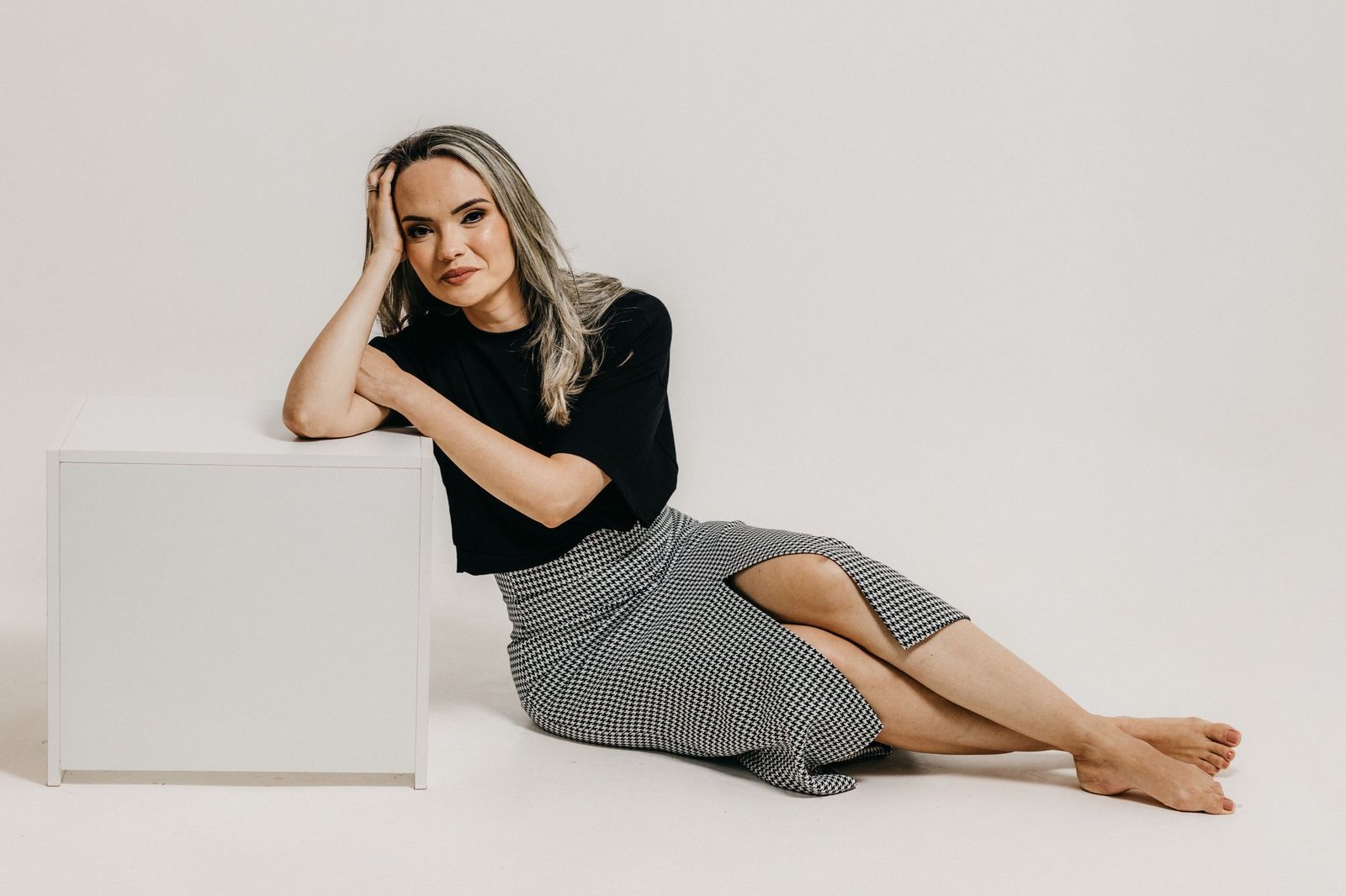 Stylish young woman posing barefoot in studio, showcasing fashion elegance.