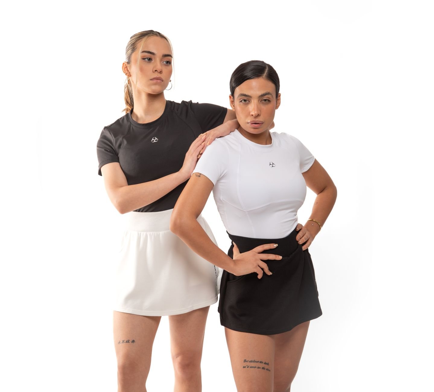 Two women in stylish sportswear posing during a studio photoshoot, showcasing athletic fashion.