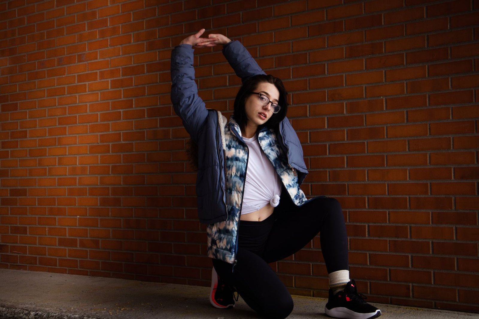 Stylish woman poses confidently against a brick wall, showcasing modern casual fashion.