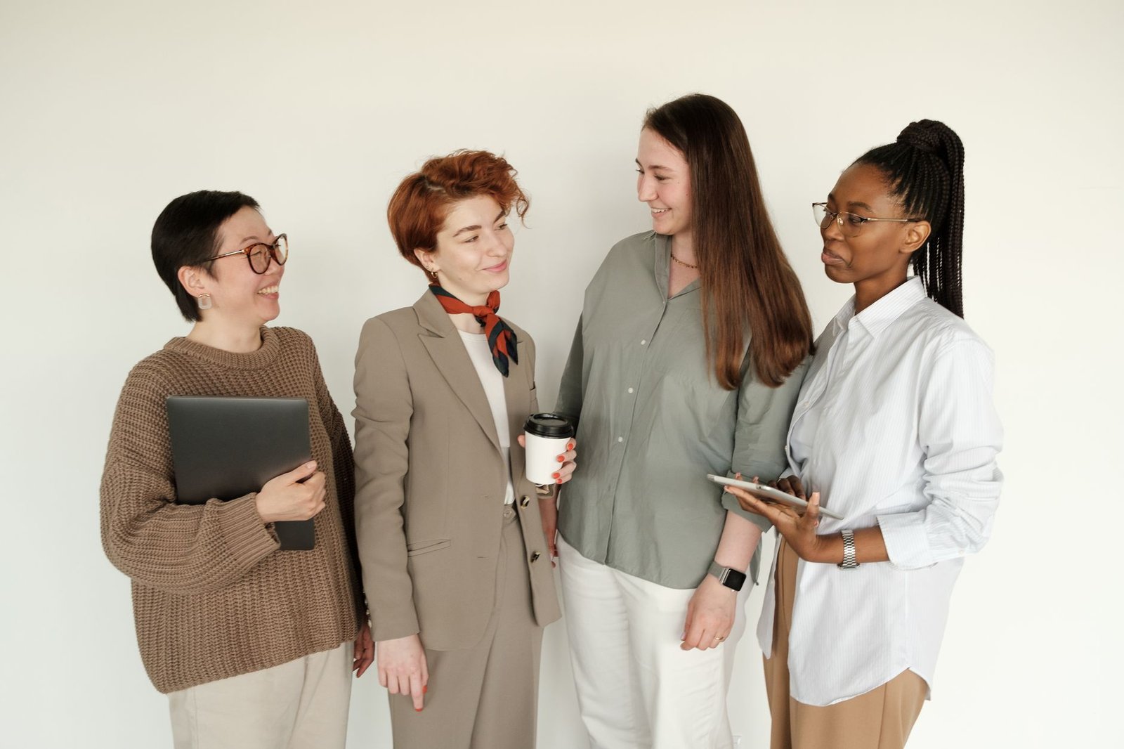 A diverse group of businesswomen engaging in a casual conversation indoors.