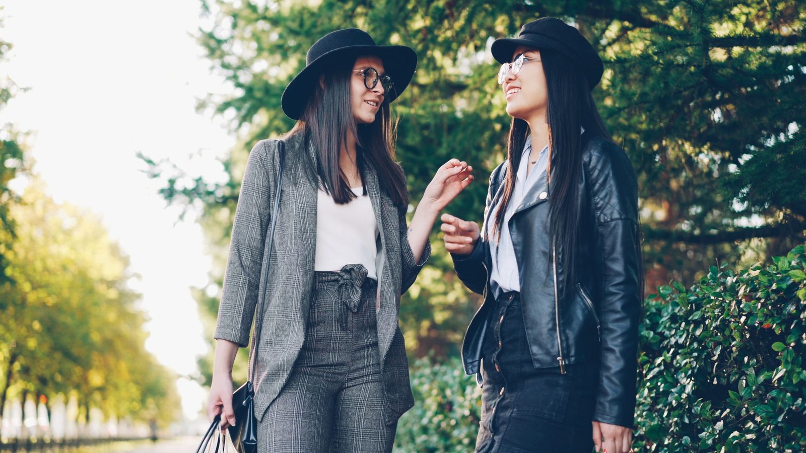 Two young women in fashionable outfits enjoying a walk outdoors in daylight.