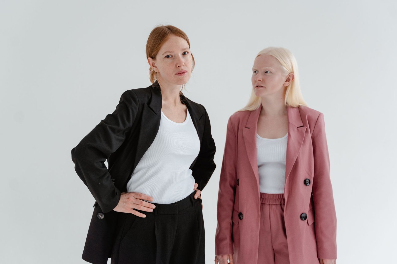 Two women in business suits exuding confidence on a white studio background.