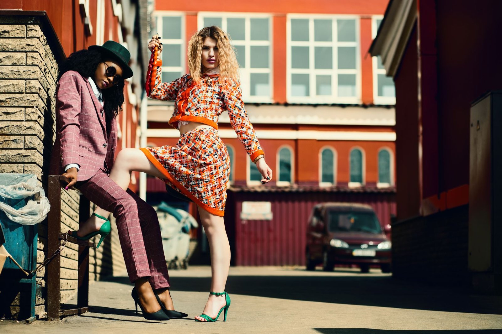 Stylish women posing in an urban alley showcasing contemporary fashion trends.