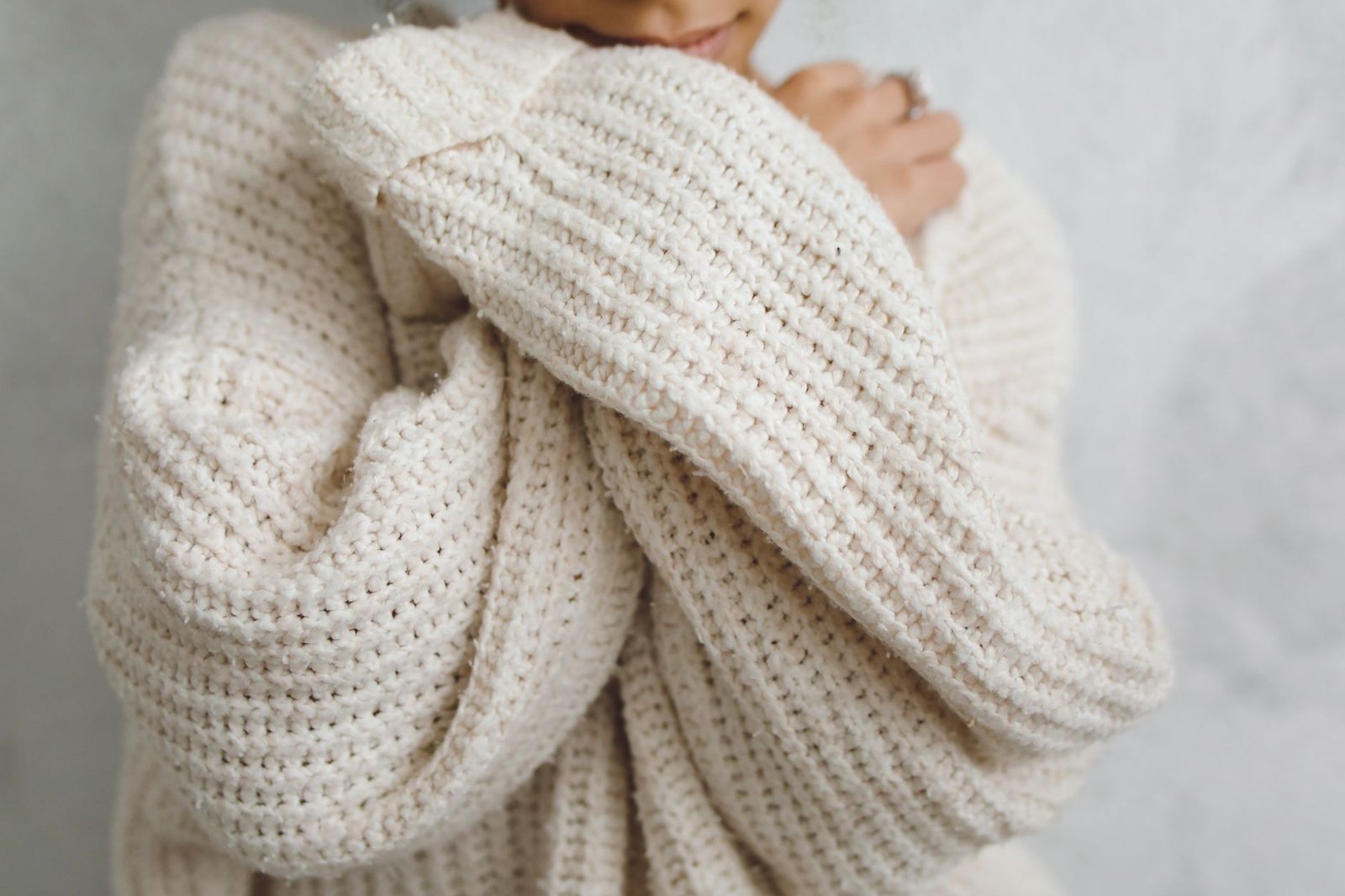 A close-up portrait of a person in a white knitted sweater with long sleeves, offering a warm and cozy feel.