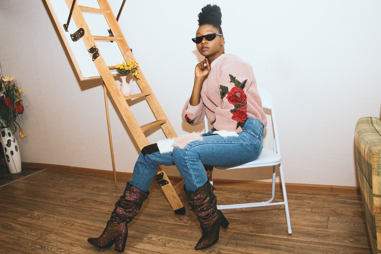 Elegant woman in a chic outfit posing indoors with sunglasses and stylish boots.