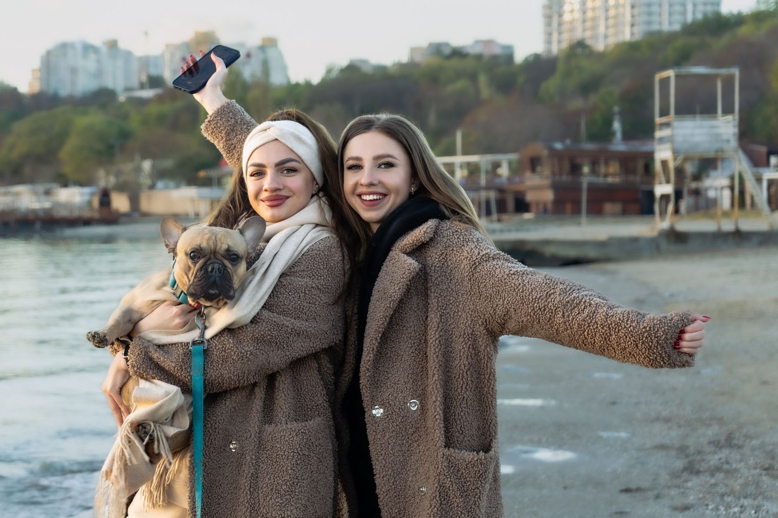 Two women smiling on a winter beach with their dog in Odessa, Ukraine.