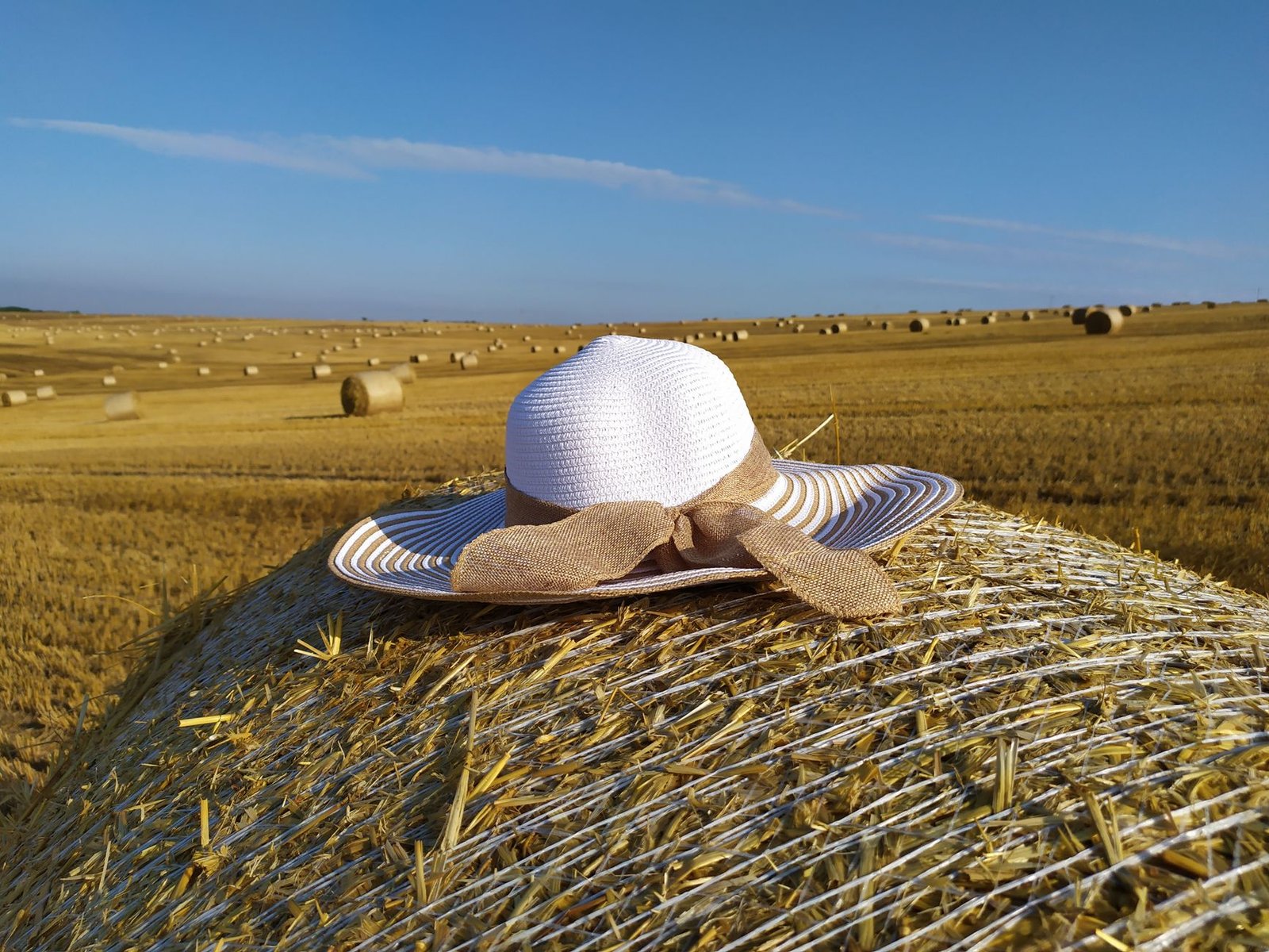 White wide brimmed hat on straw bale in sunny Czech field.