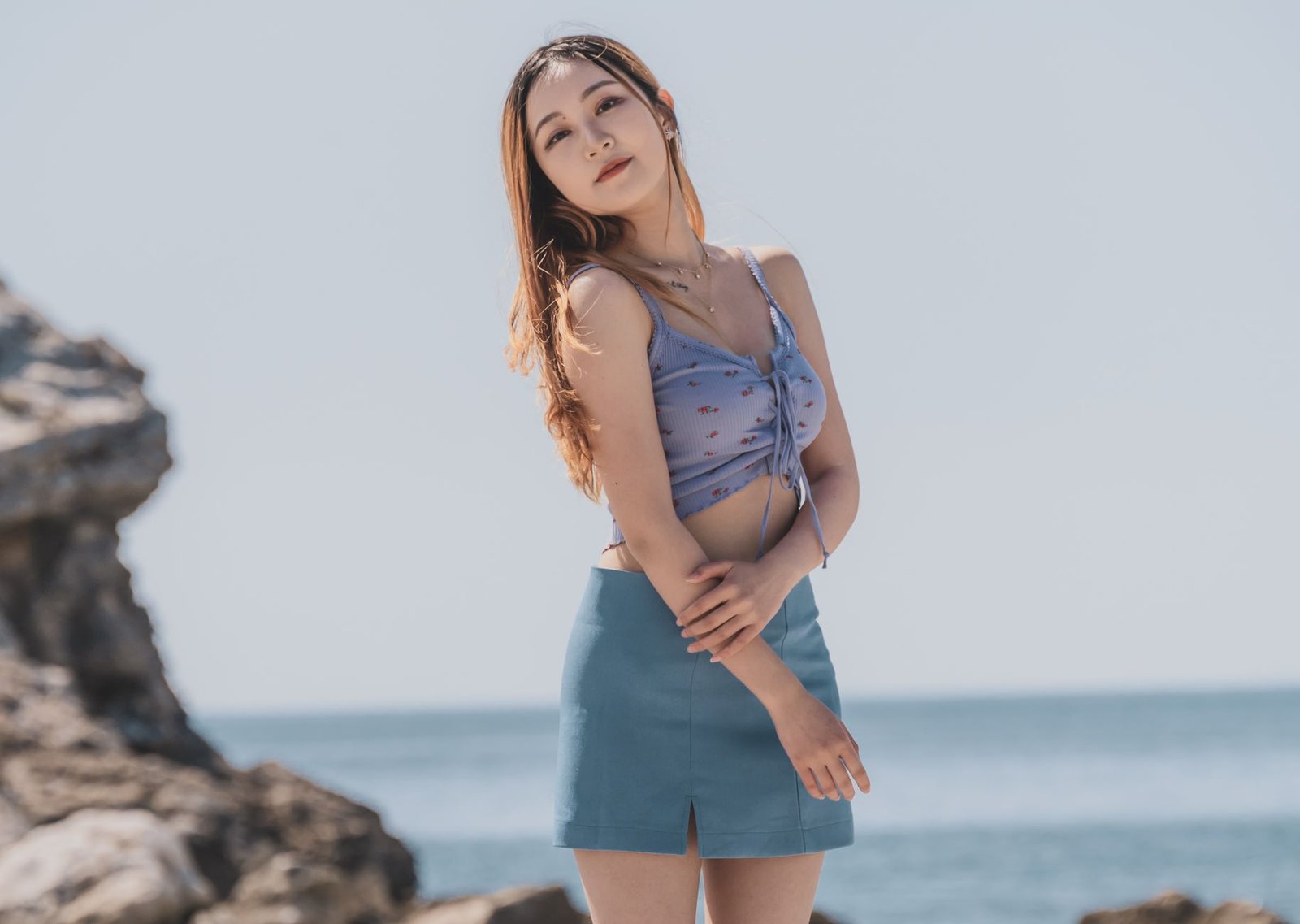 A stylish woman poses confidently by the sea, showcasing summer fashion in Montenegro.