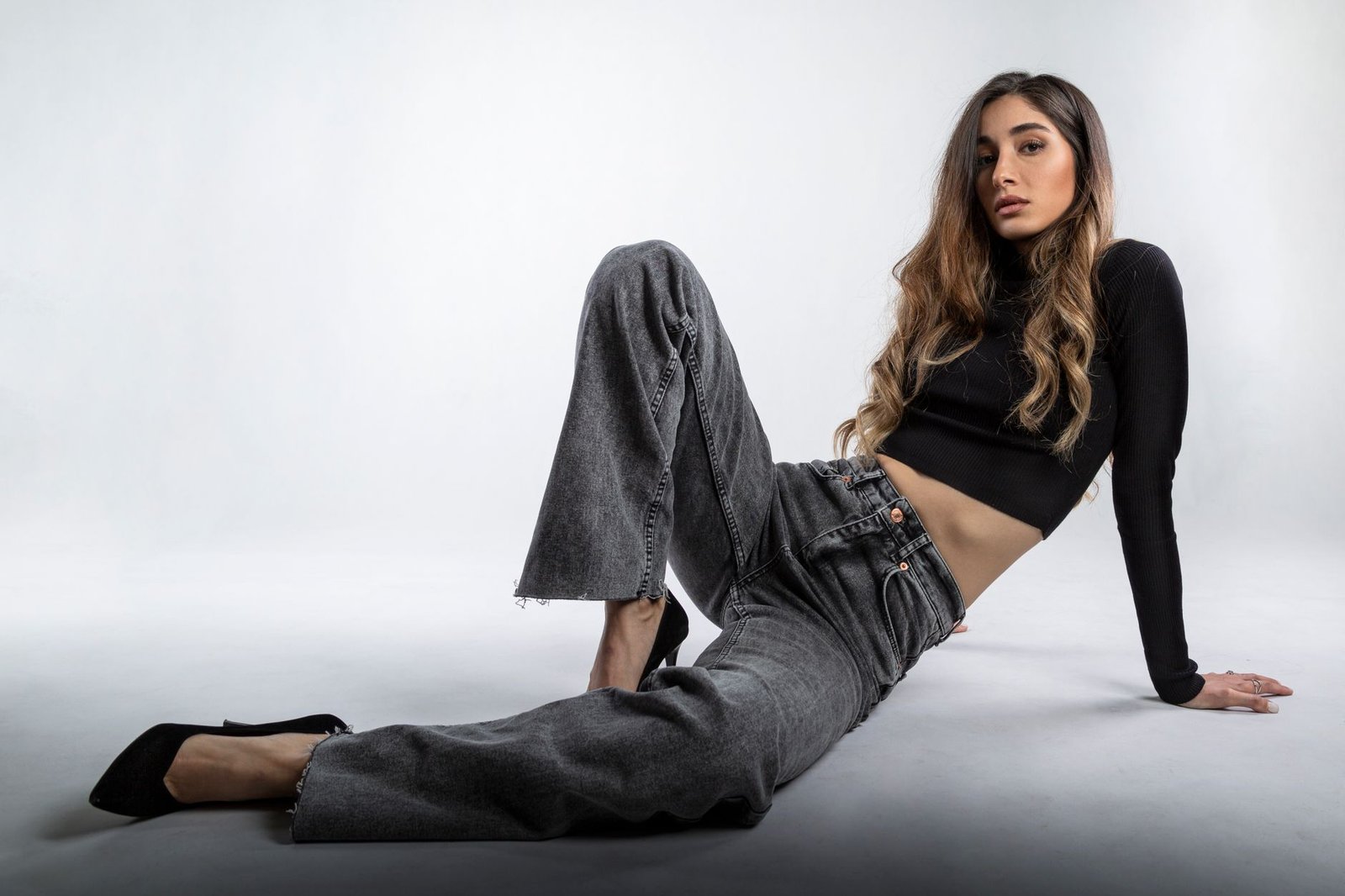 Young woman in fashion-forward outfit posing on a neutral background.
