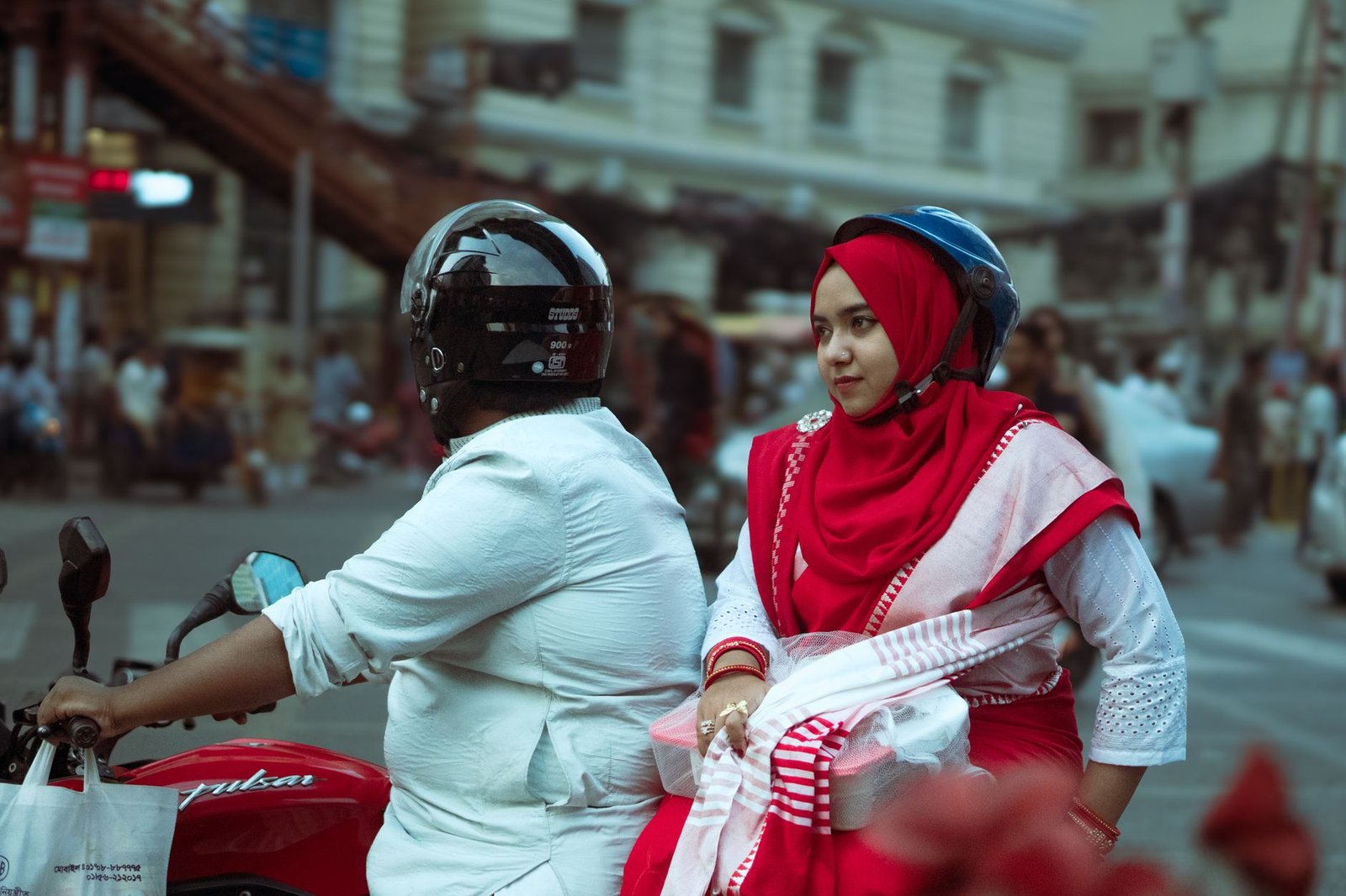 A candid street portrait of a woman in Dhaka on a motorcycle. Vibrant urban scene.