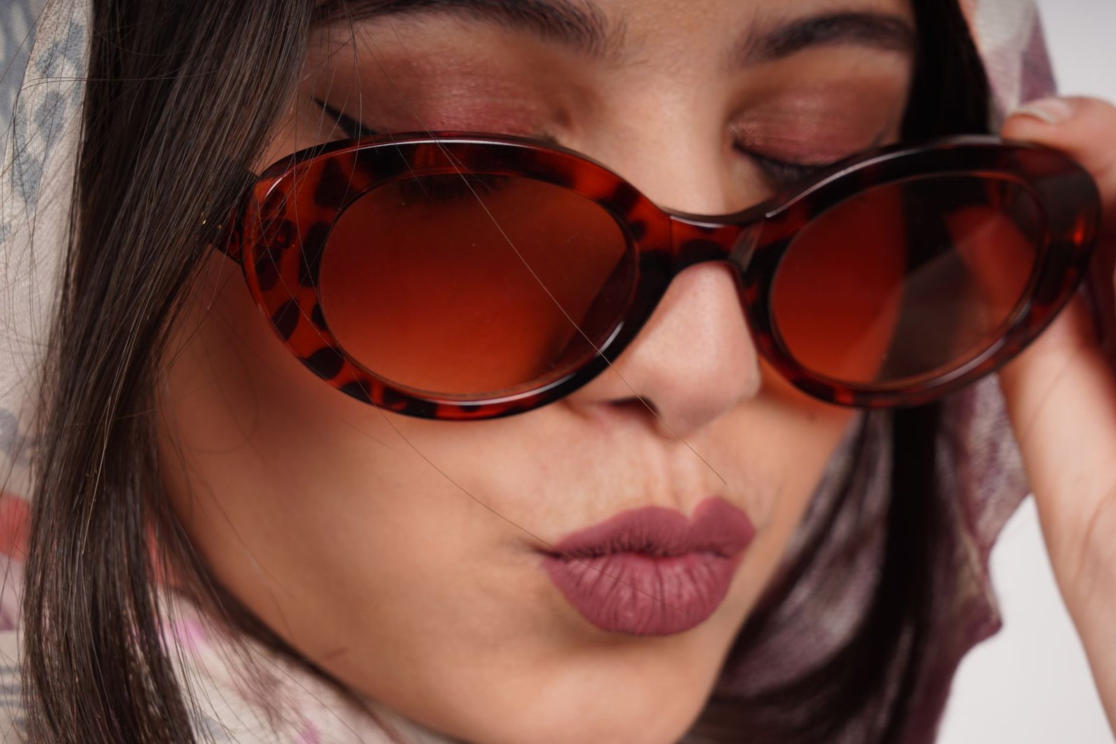 Fashionable close-up of an adult woman wearing stylish sunglasses with a trendy expression.