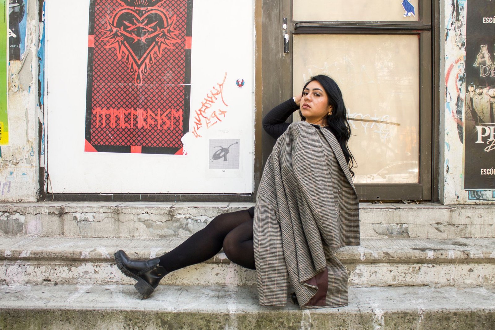 Confident woman poses on urban steps in a fashionable setting.