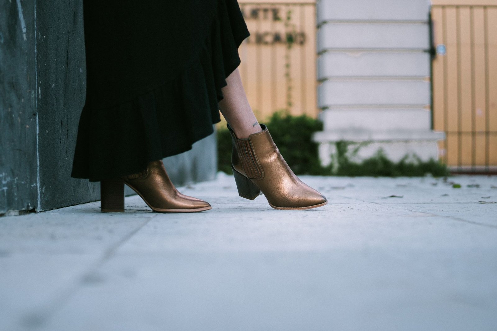 Chic metallic boots paired with a black skirt in an urban street setting.