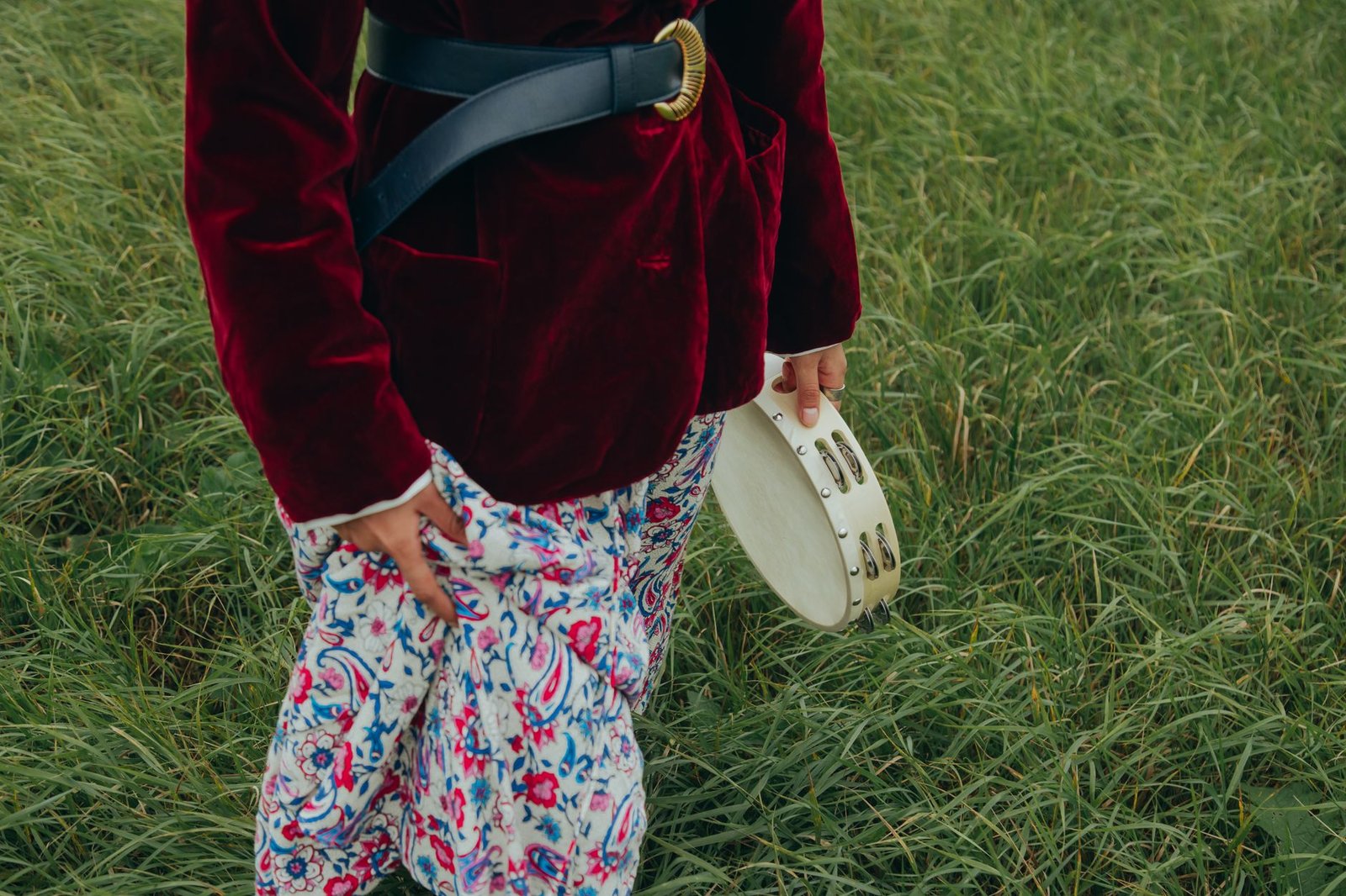 Woman in bohemian outfit holding a tambourine outdoors.