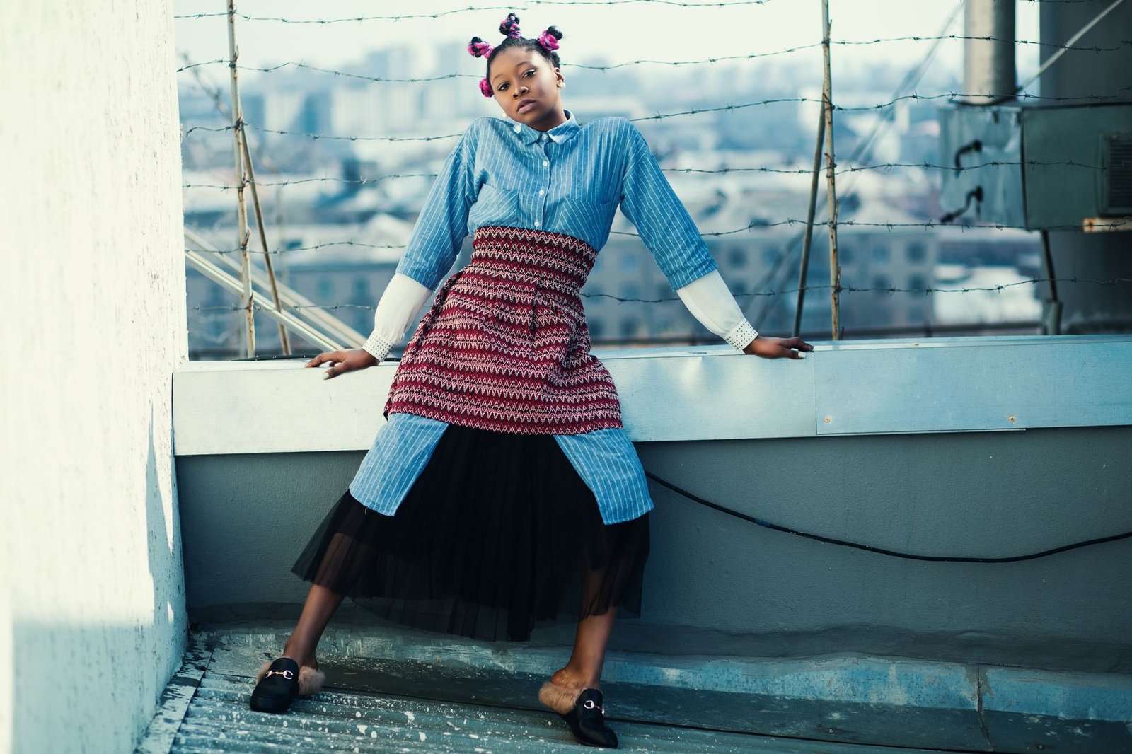 Young woman posing in a fashionable outfit on a rooftop, showcasing urban style.