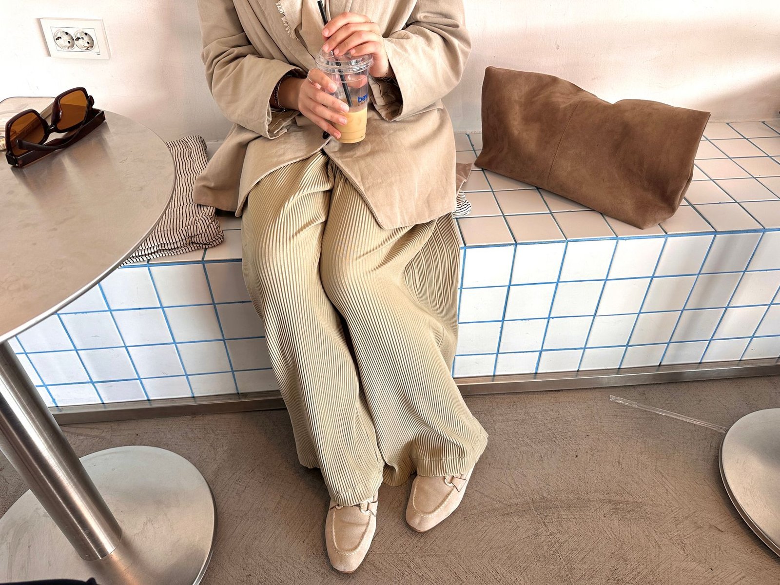 Casually dressed individual enjoying iced coffee in a modern café setting.