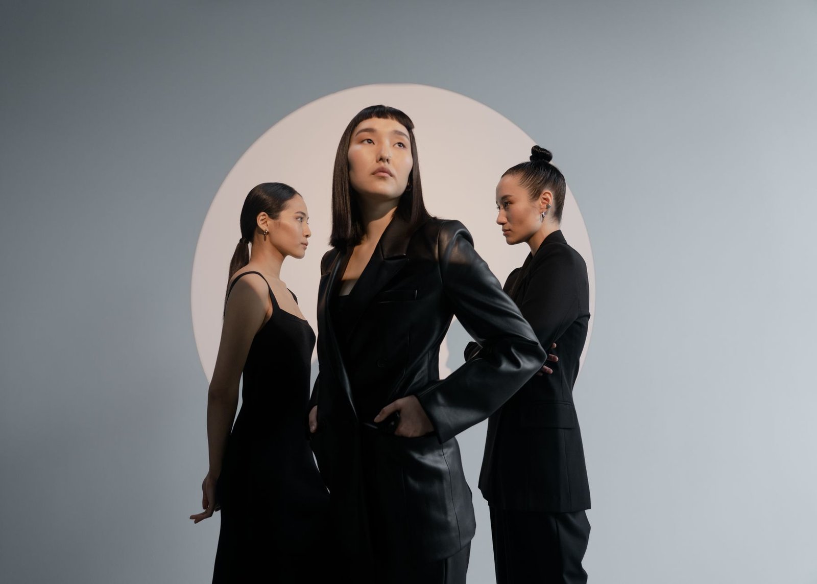 Group of Asian women in black outfits posing in a modern studio.