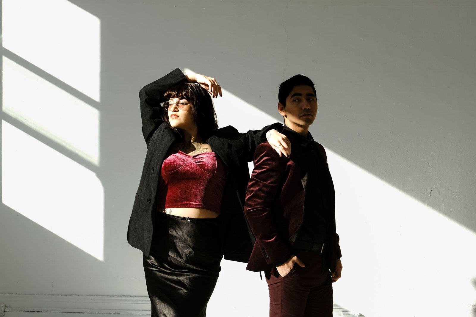 Elegant portrait featuring two individuals in contrasting lighting, highlighting fashion and style.