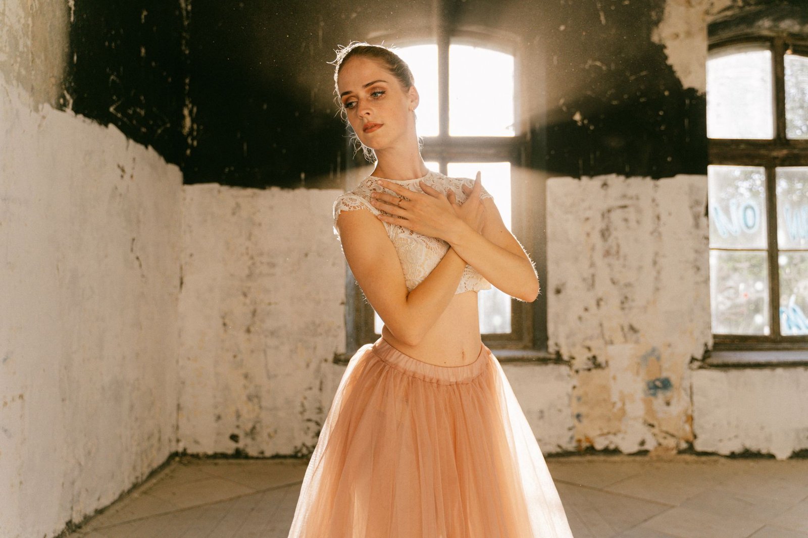 Graceful woman in lace top and tutu, bathed in natural light indoors.