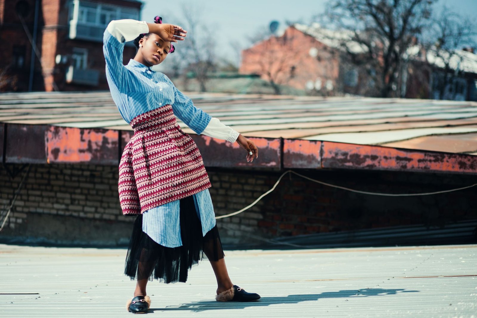 Fashionable woman posing on a rooftop. Creative urban style captured outdoors.