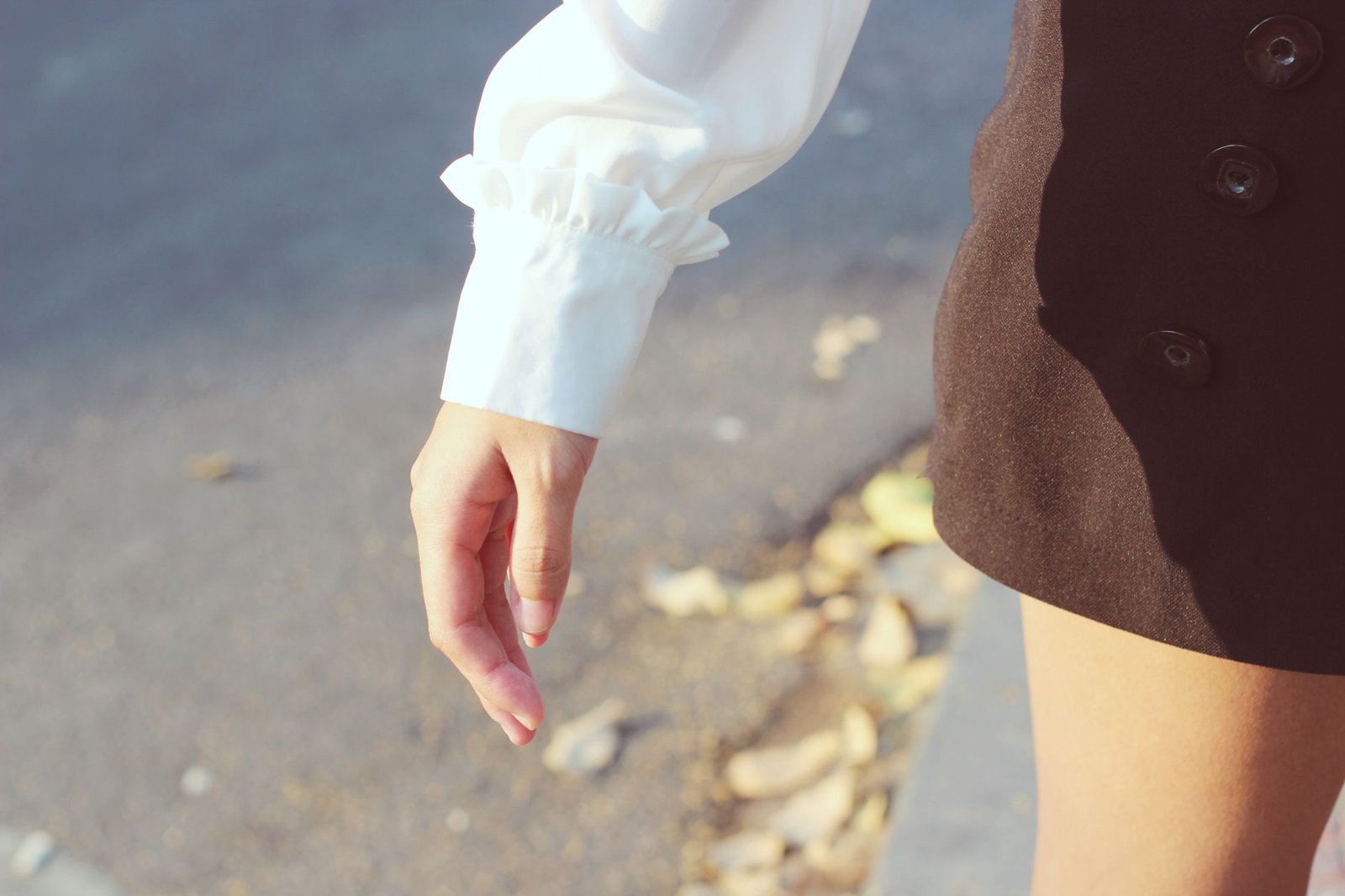 Close-up of a woman in a black skirt and white blouse walking outside on a sunny day.