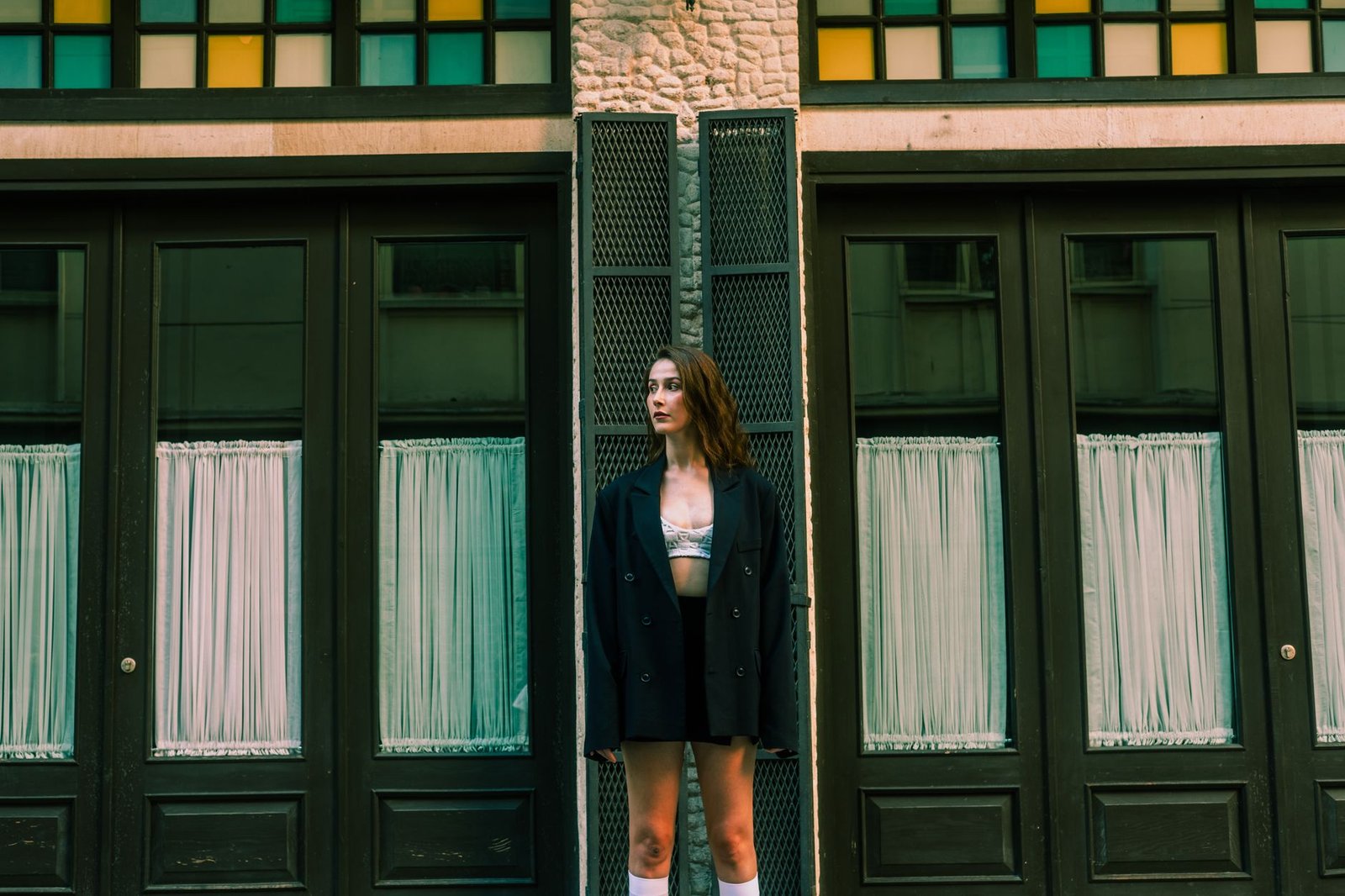 Stylish woman posing against urban building façade, showcasing modern fashion
