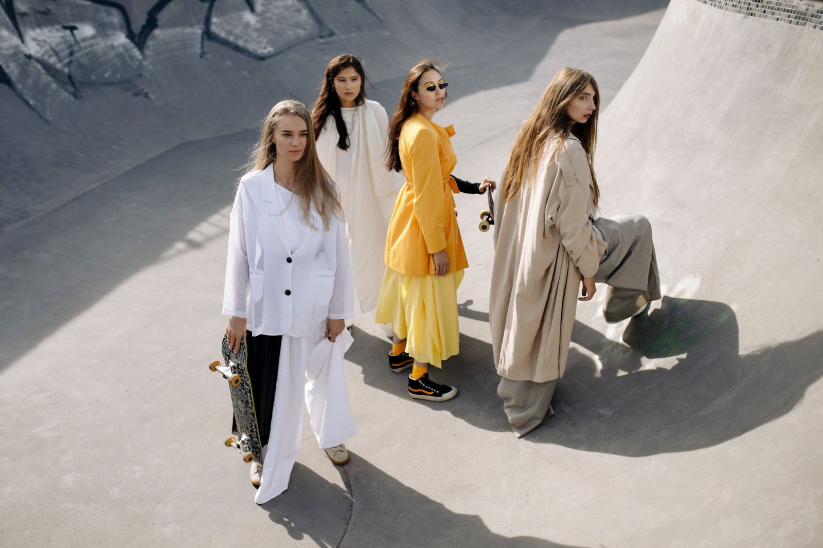 Stylish women posing creatively at a skate park in modern outfits.