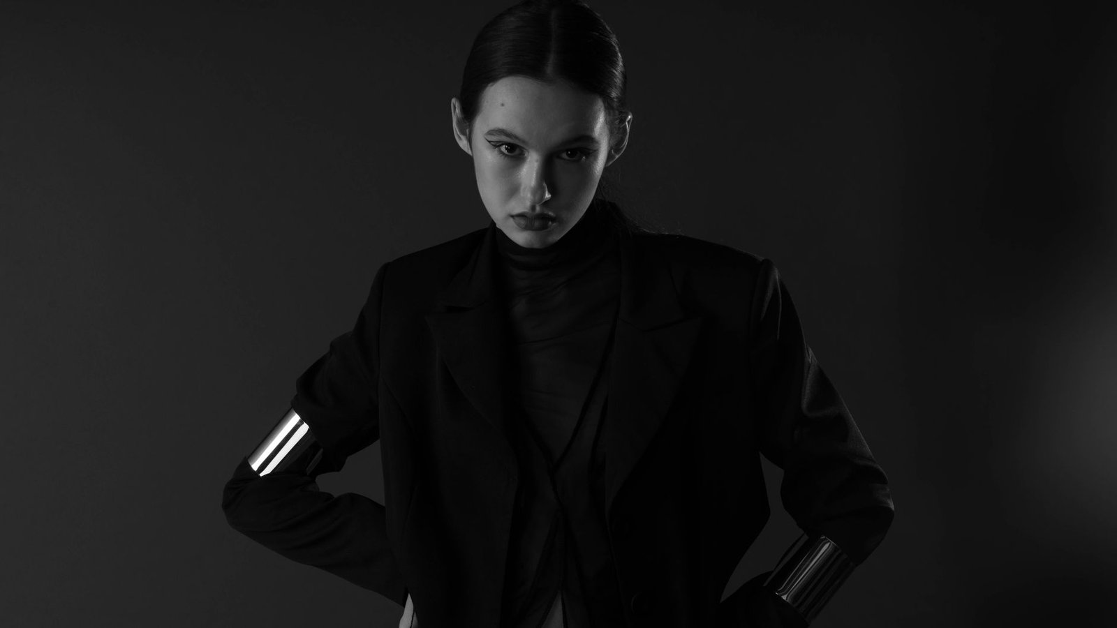 Striking black and white fashion portrait of a woman with an intense gaze, wearing a stylish ensemble.