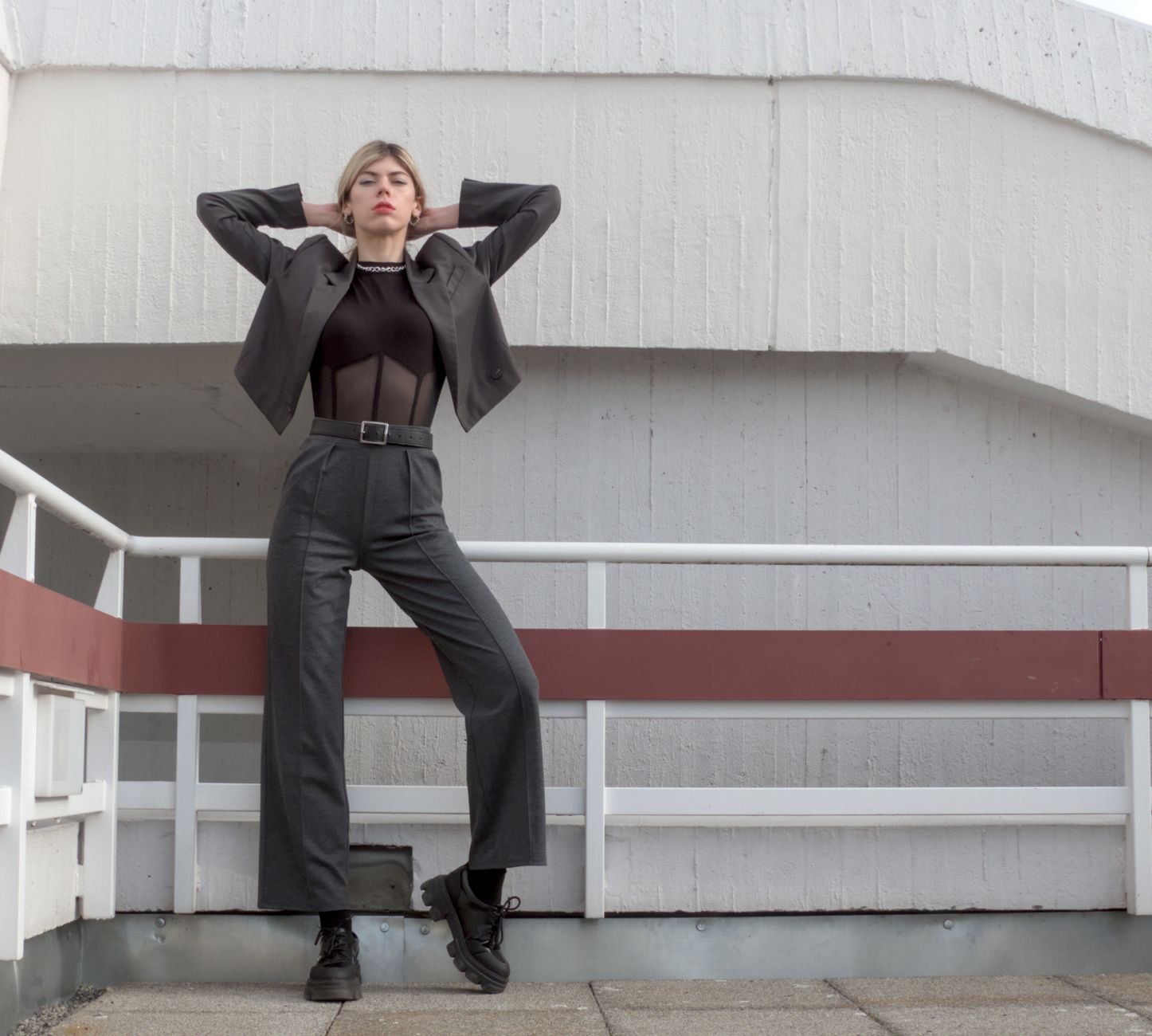 Stylish woman posing confidently in a modern outfit on an urban staircase.