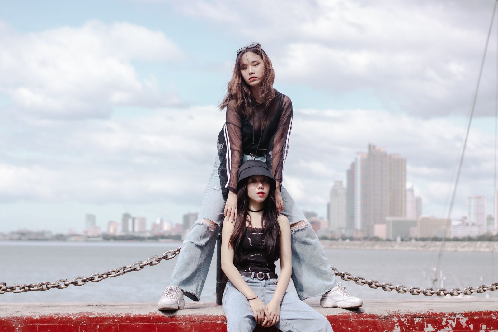 Two stylish young women posing by the waterfront with Manila skyline in the background.