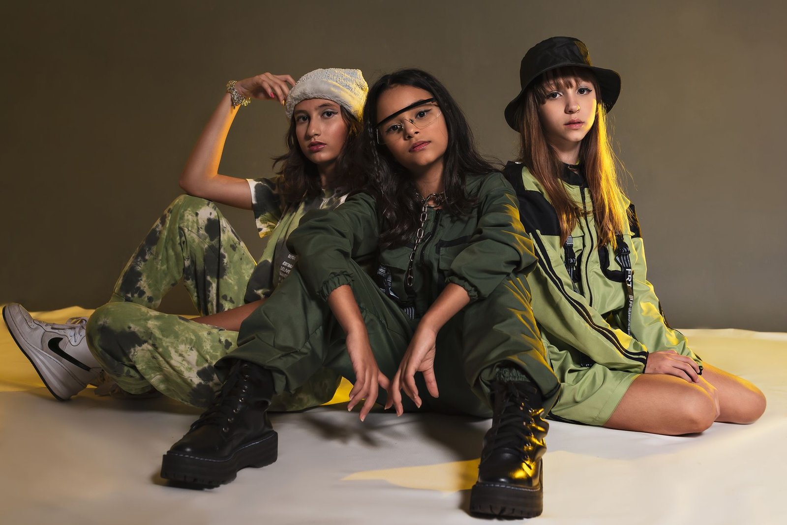 Three teenagers in trendy urban outfits posing confidently indoors.