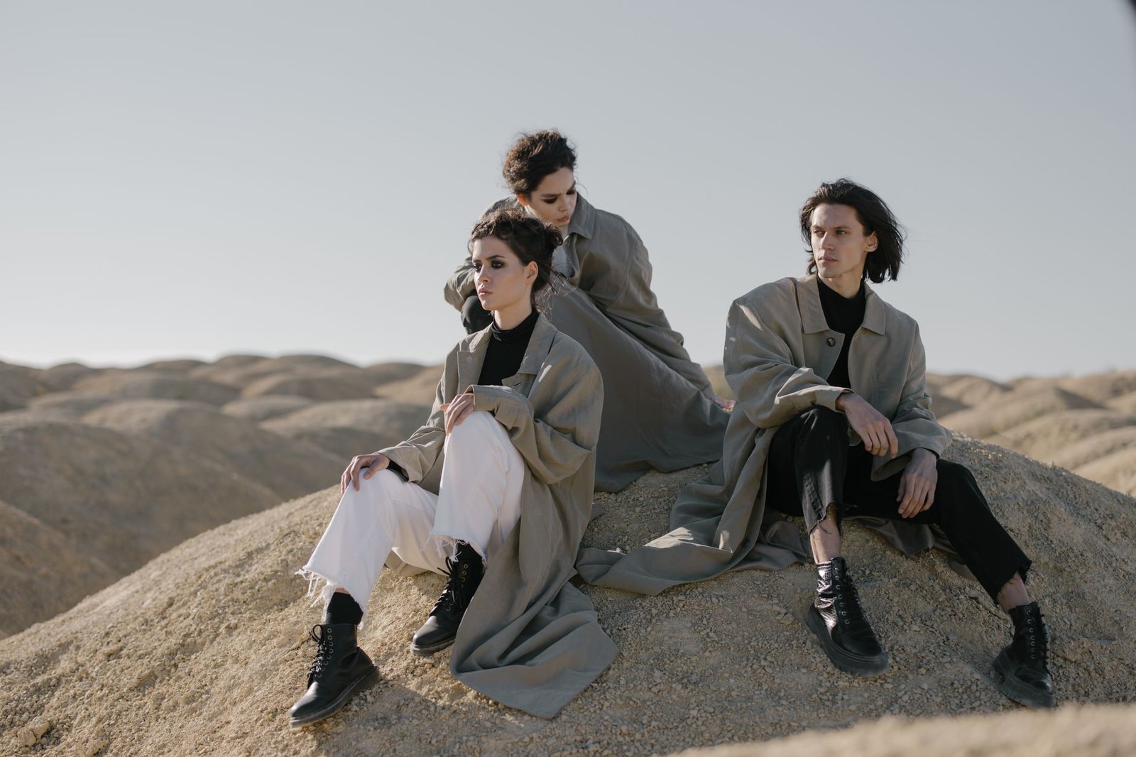 Fashionable group wearing trench coats posing in a serene desert setting.