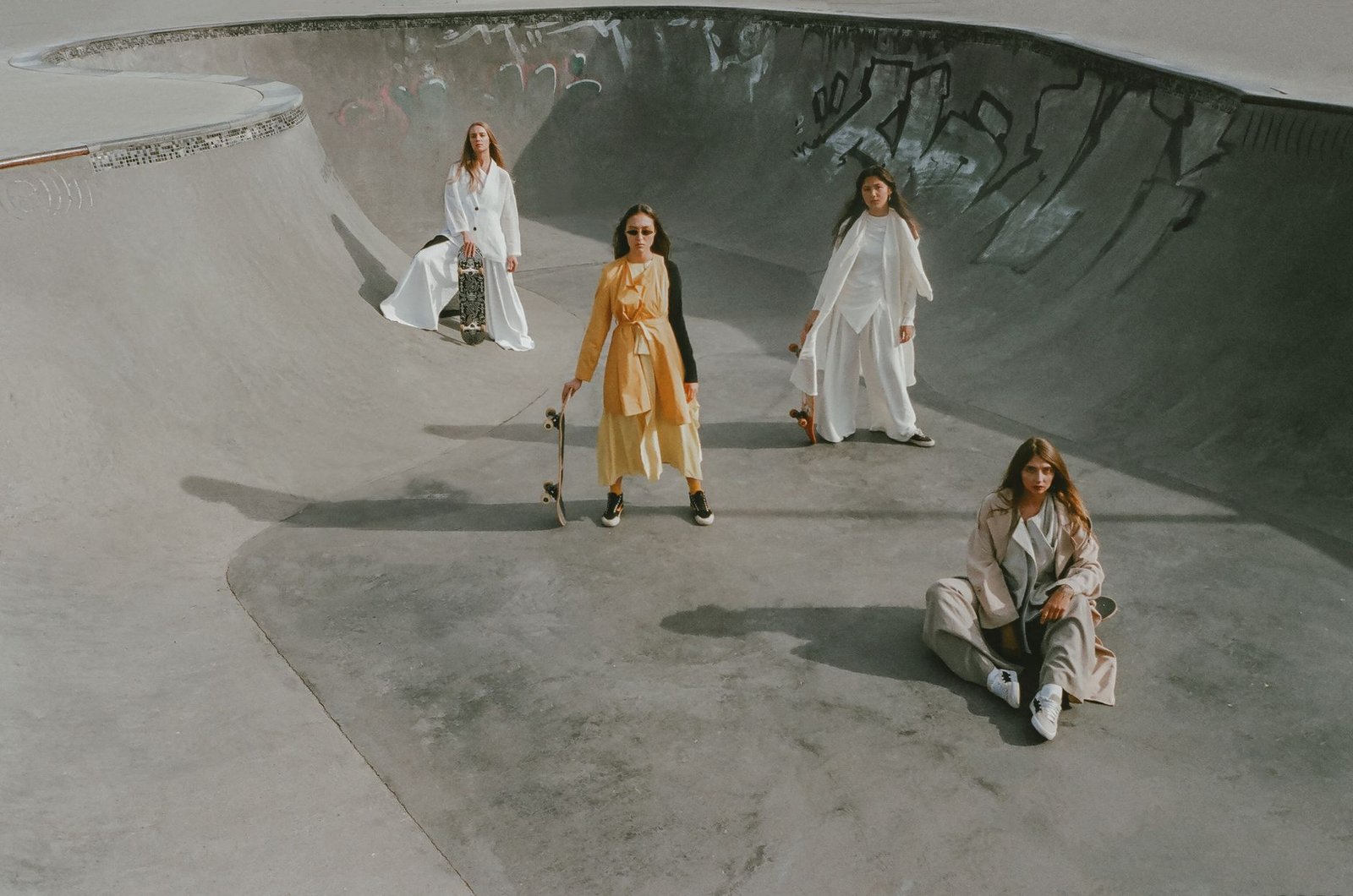 Stylish models in oversized outfits captured at an urban skate park with artistic graffiti.
