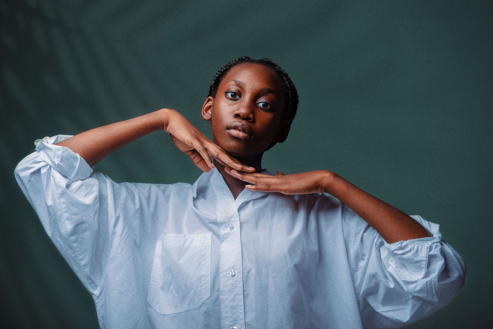 Portrait of a woman in a white shirt posing against a green background.
