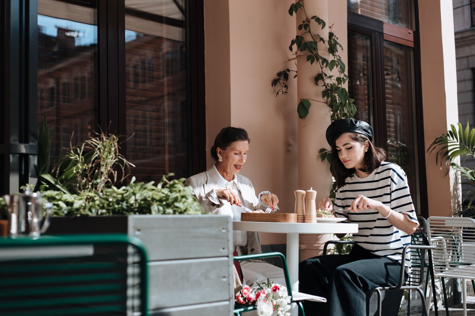 Stylish women enjoy a relaxed outdoor café brunch, capturing elegance and warmth.