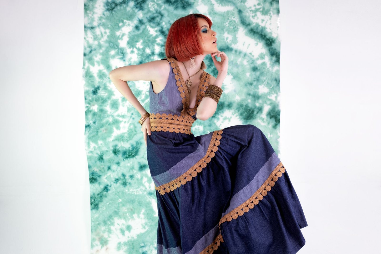 Striking fashion portrait of a woman posing against an artistic green backdrop.