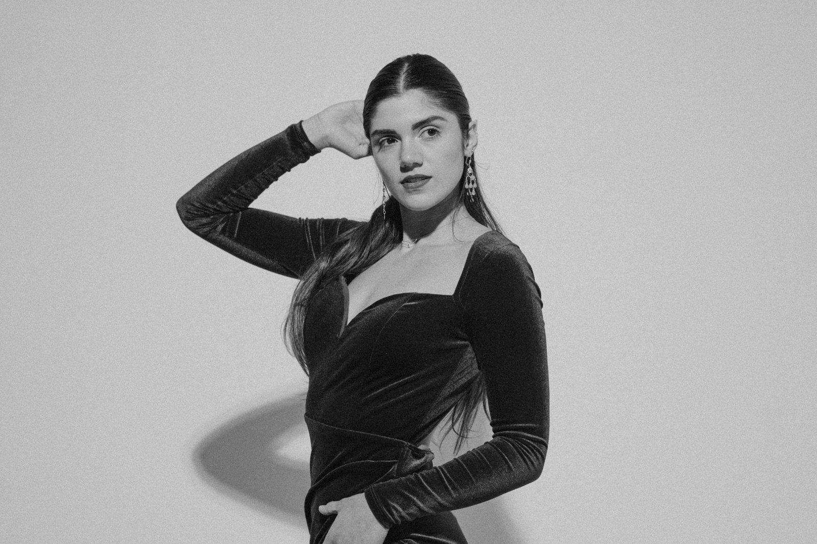 Stylish black and white studio portrait of a woman in a glamorous dress striking a pose.