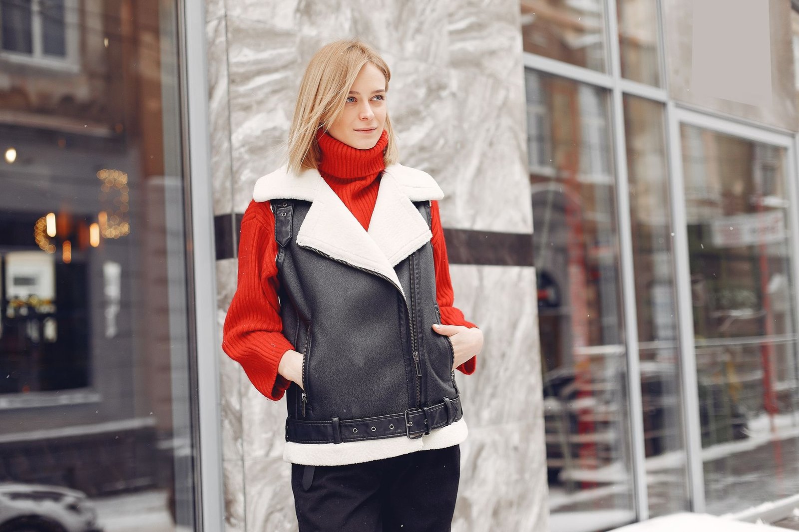Fashionable woman poses in winter clothes on city street, blending style with warmth.